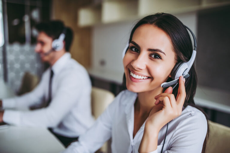 Smiling contact centre worker wearing a headset while assisting a customer.