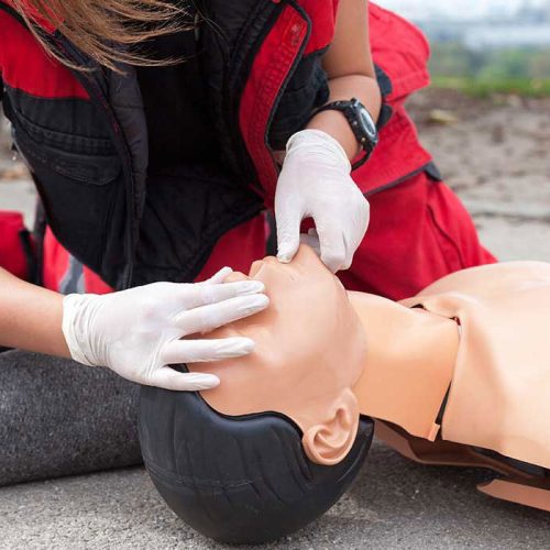 Instructor demonstrating CPR on a training mannequin during a health and safety course.